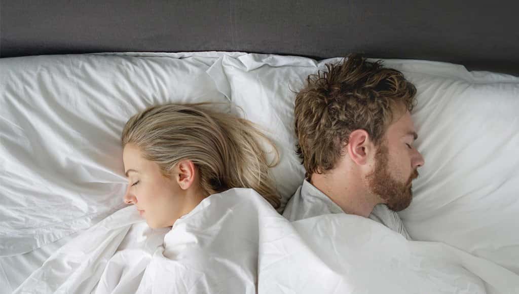 رجل وامرأة نائمان بجانب بعضهما على السرير