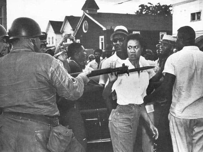 (غلوريا ريتشاردسون) Gloria Richardson تُبعِد حربة أحد الحراس الوطنيين خلال احتجاج في (كامبريدج – ماريلاند، انجلترا)، 1963.