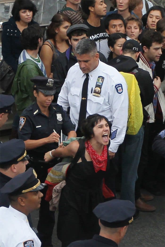 الشرطة تعتقل متظاهرة تابعة لحركة ”احتلال وول ستريت“ Occupy Wall Street، بعد أن قامت مع رفاقها بمحاولة لعبور جسر (بروكلين) Brooklyn على الطريق السريع، شوهدت المرأة المُعتَقَلة تصرخ باسمها عالياً لكي يسمعه الداعمون على جسر المشاة، الذين يسجلون أسماء الأشخاص الذين تمَّ اعتقالهم.