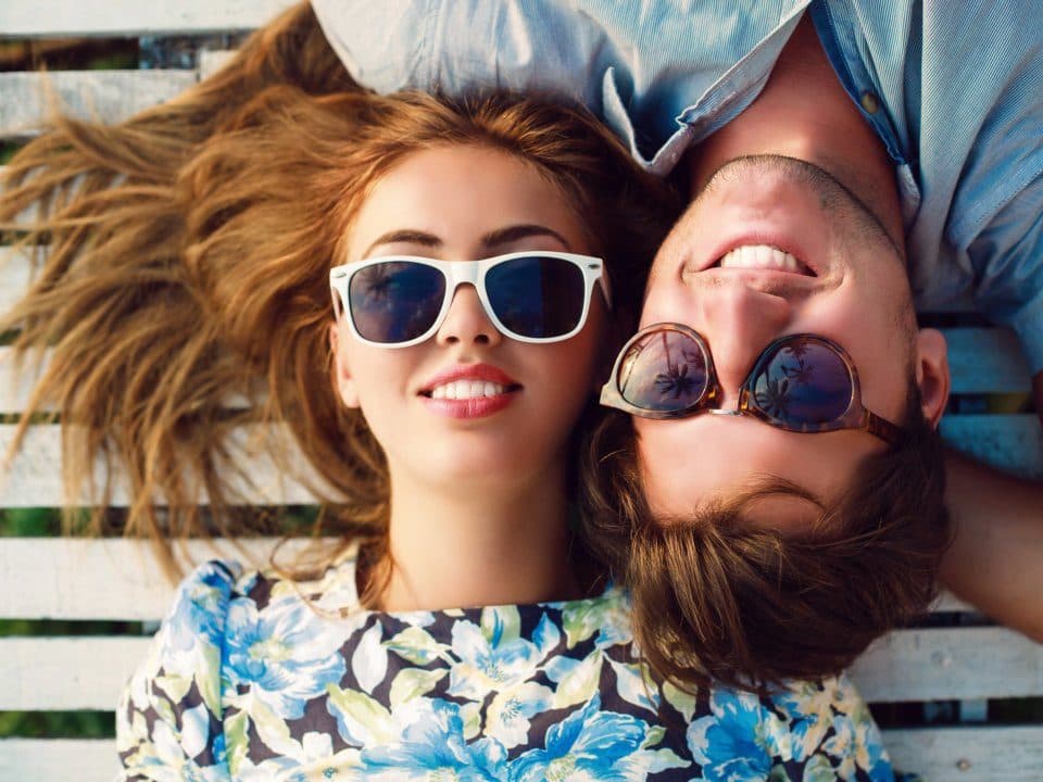 شابة وشابة مستلقيان يرتديان نظارات شمسية ويبتسمان