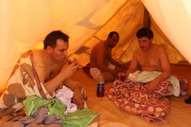 مرضى يشربون الشاي داخل خيمة تستعمل وكأنها حمام سونا بينما يسترخون بعد حمام الرمل الساخن في (سيوا) بمصر.