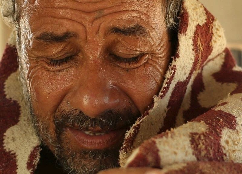 مريض يجلس داخل سيارة ملتحفا ملاءة بعد تلقيه لعلاج حمام الرمال الساخنة في (سيوا) بمصر.