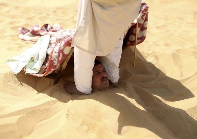 مريض يتلقى تدليكا من طرف أحد العمال الذي يقف على أكتافه ويضغط عليها بقدميه