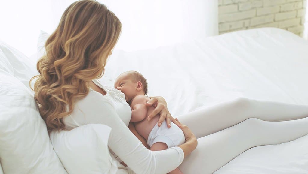 امرأة ترضع صغيرها في الفراش