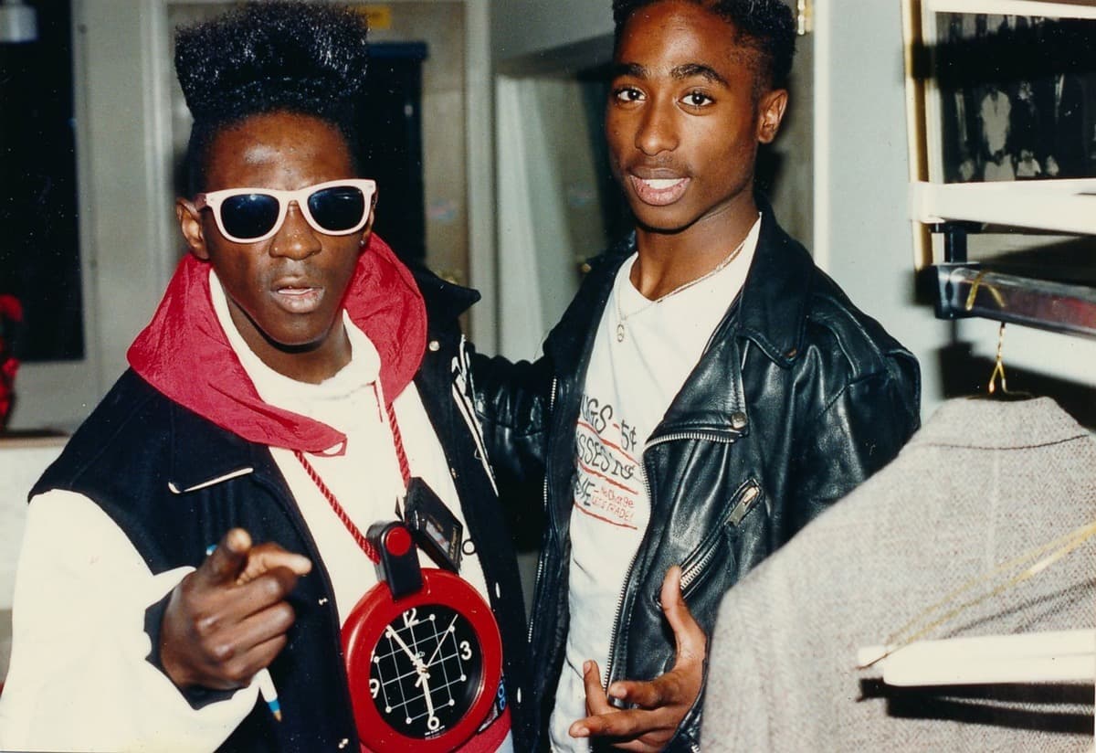 (فلايفر فلاف) Flaver Flav واقف بجانب مغني الراب الأشهر على الإطلاق (توباك شاكور) وهما يحييان المعجبين خلف الكواليس خلال حفل توزيع الجوائز الموسيقية في (لوس أنجلوس) في كاليفورنيا سنة 1989.