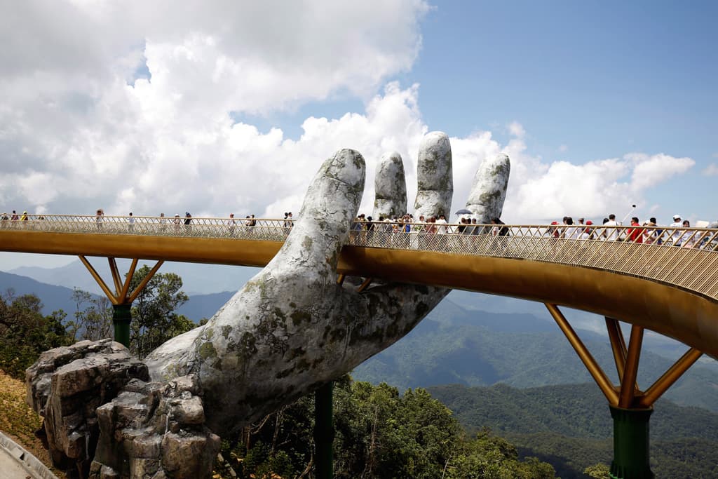 سياح يتمشون عبر مجسم ضخم لليد البشرية على الجسر الذهبي في منتجع (بانا هيلز) Ba Na Hills في فيتنام