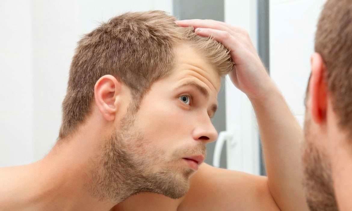 رجل ينظر إلى المرآة متفقداً شعره.