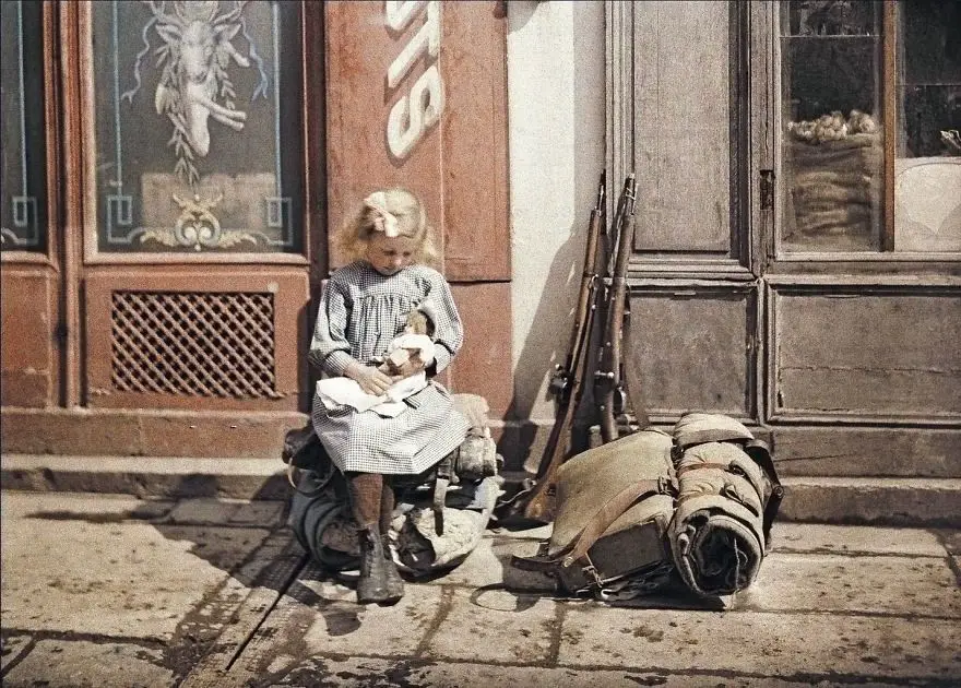 فتاة تحمل دمية بجانب المعدات الحربية لجندي في ”رايمس“، فرنسا، سنة 1917