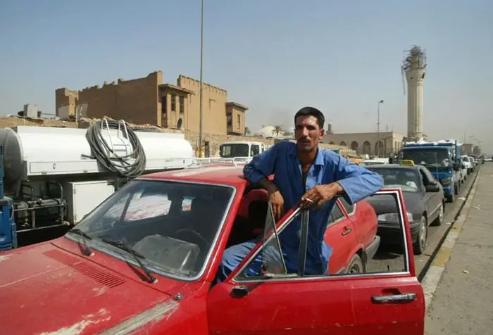 مواطن عراقي يدخن سيجارة خارج سيارته خلال ازدحام مروري في مركز العاصمة (بغداد)
