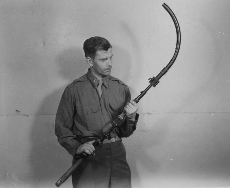 رجل يحمل بندقية مع أنبوب منحني موصول بها خلال الحرب العالمية الثانية.