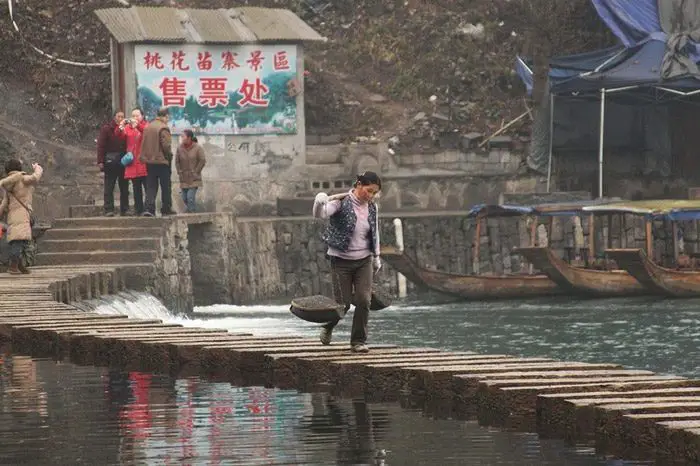 امرأة تقطع نهرا على ممشى في الصين