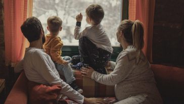 صورة عائلة تضم أم وأب وطفلين ينظرون من خلال النافذة
