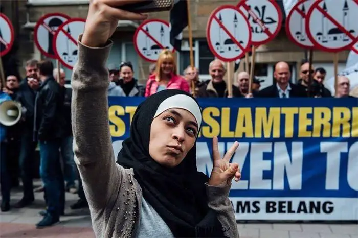 زكية بلخيري تأخذ صورة ”سيلفي“ خلال تظاهرة ضد المسلمين في (أنتويرب – بلجيكا) في 2016.