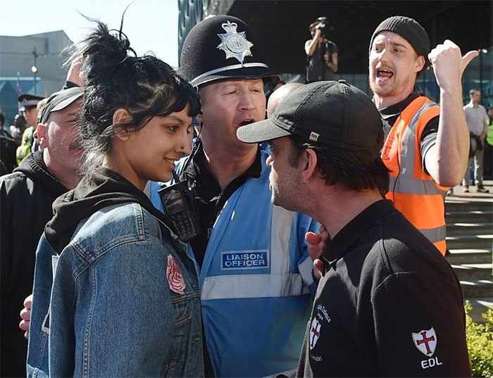 صورة لـ(صفية خان) Saffiyah Khan وهي تبتسم في وجه محتَجٍّ من رابطة الدفاع الانجليزية (Edl) في (بيرمينغهام)، الذي قطع عليها الطريق بعد أن تقدمت للدفاع عن زميل لها.