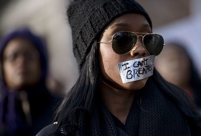 امرأة تستمع لأحد المسيرات وفمها مغلق بشريط، خلال زحف ”العدالة للجميع“ في شارع كولومبيا في واشنطن في الولايات المتحدة الأمريكية، بتاريخ 13 كانون الأول/ديسمبر 2014.