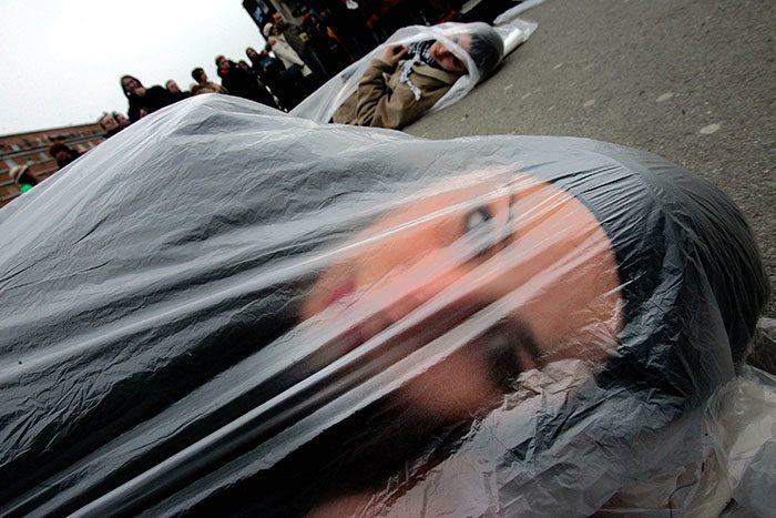 عدد من النساء مستلقياتٍ على الأرض ومغلَّفات بأكياس بلاستيكية، كإشارة للاحتجاج في وسط مدينة (نوفيساد) في صربيا، في 10 كانون الأول/ديسمبر 2005.