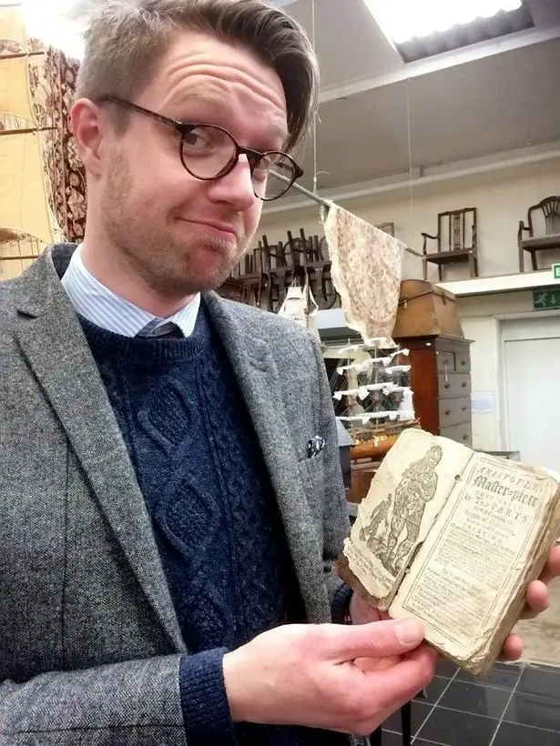 (جيم سبنسر)، مقيم كتب ومخطوطات في المزاد العلني (هانسون) في (إتوال)، بـ(داربيشاير)، يحمل في يده (كتيب الجنس) من سنة 1720.