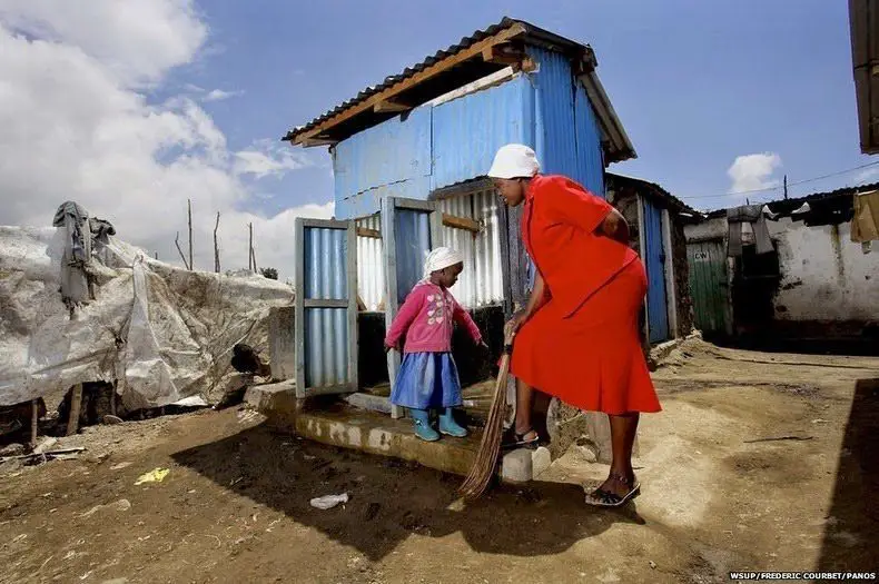 امرأة كينية مع ابنتها أمام مرحاض خارجي