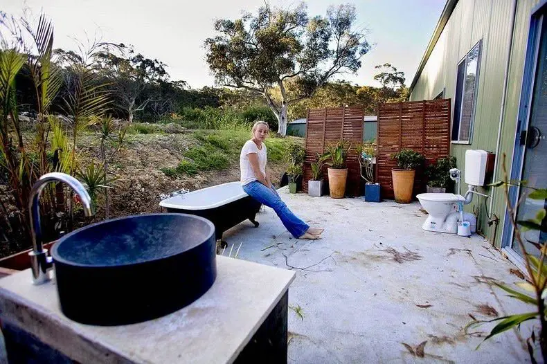 امرأة أسترالية خارج منزلها أمام مرحاض خارجي