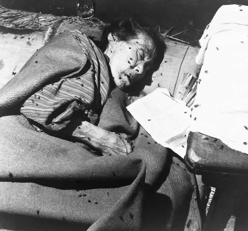 صورة لعجوز نجت من الكارثة وهي مستلقية والذباب يغطي جسدها في أحد البنوك التي أصبحت مشفى ميدانيا لضحايا الحادثة.
