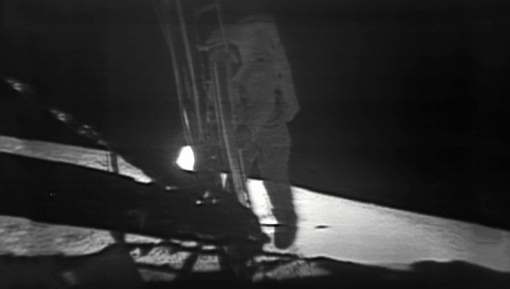 نيل أرمسترونغ لدى نزوله من مركبة (لونار موديل): هذه صورة التقطت بواسطة الكاميرا التلفزيونية ذات التصوير البطيئ، والدقة المنخفضة المركّبة على متن المركبة القمرية (لونار موديل) Lunar Model باختصار LM التي أطلقها (نيل أرمسترونغ) قبل نزوله عبر سلالم المركبة من خلال سحب شريط.