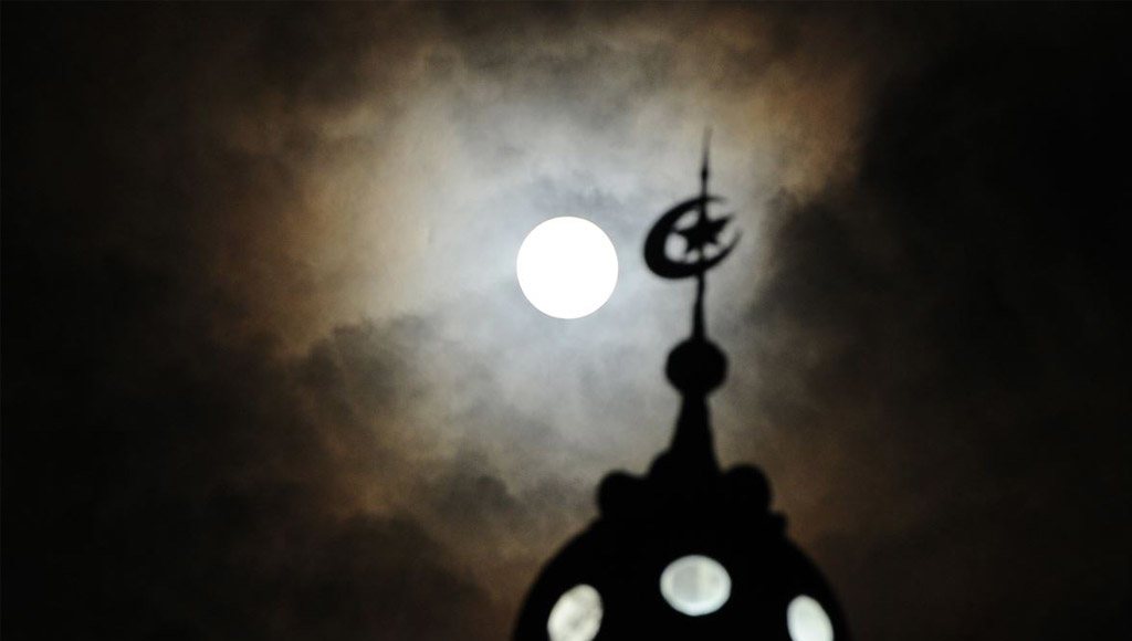 مأذنة مسجد إسلامي مع القمر في الخلفية ليلا