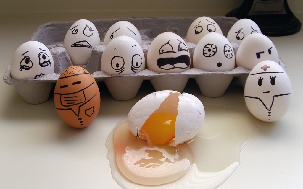 بيضة مكسرة بجانب بيضات أخريات مرسوم عليها تعابير وجوه