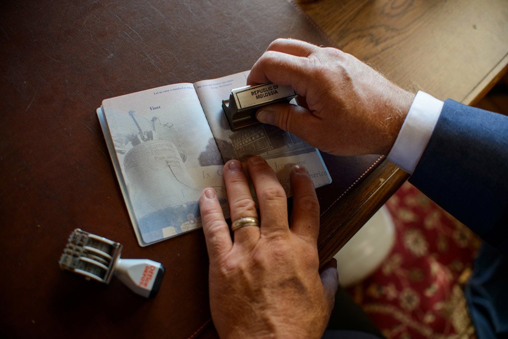 يختم الرئيس Baugh أحد جوازات السفر بالختم الخاص بالدولة