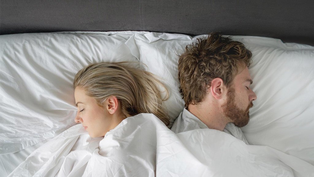رجل وامرأة نائمان بجانب بعضهما على السرير