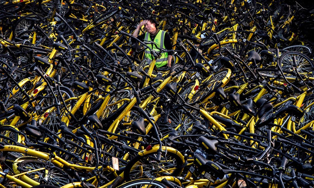 ميكانيكي يعمل لصالح شركة مُشاركة الدراجات (أوفو) يقف حائراً بين أكوام الدراجات العاطلة التي تحتاج لتصليح في العاصمة الصينية (بكين)