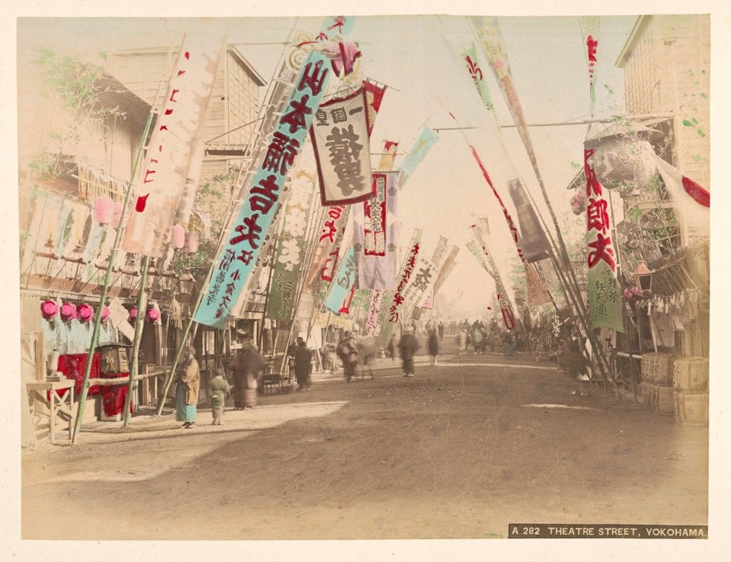 شارع مليء بالمسارح في (يوكوهاما) تمتد عبره طريق مليئة باللافتات الإعلانية للعروض في داخلها حوالي سنة 1890