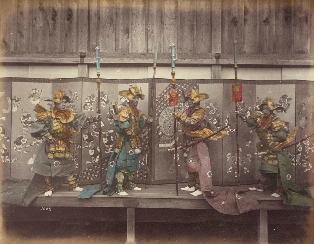 أربعة رجال يرتدون ملابس عسكرية متقنة الصنع يؤدون عرضهم على خشبة المسرح حوالي سنة 1880 للميلاد