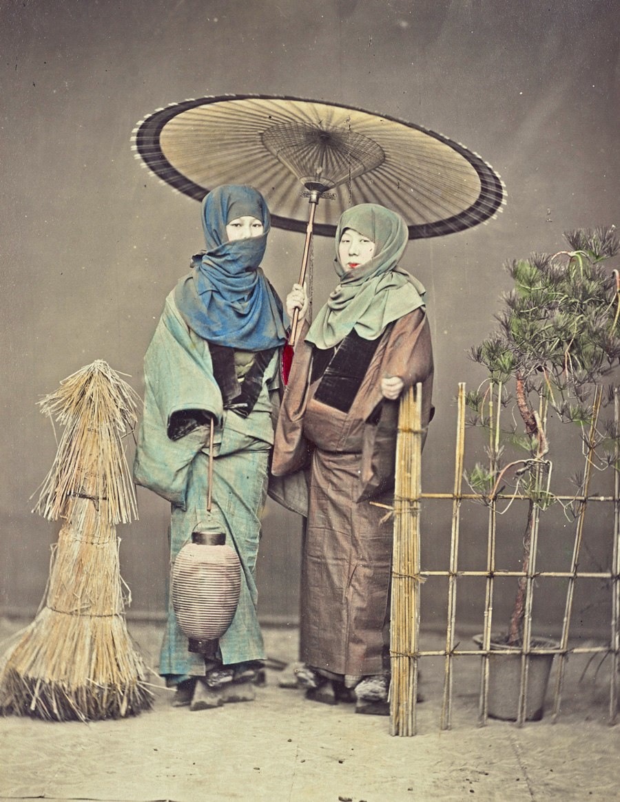 امرأتان تقفان في الخارج، تحمل إحداهما مظلة من الورق والأخرى فانوسًا ورقيا بين عامي 1870 و1900
