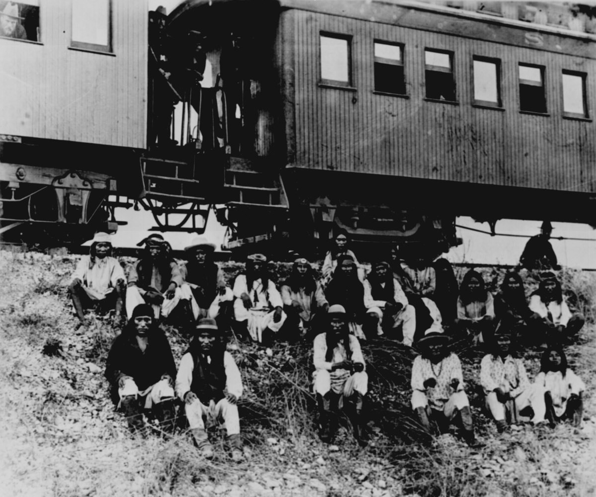 مجموعة من الآباتشي من ضمنهم بطل الحرب (جيرونيمو) بعد استسلامهم للجنرال (مايلز) بمحاذاة نهر (نويسيس) في (تكساس) سنة 1886: سيقوم القطار الذي خلفهم بنقلهم إلى ديار المنفى.