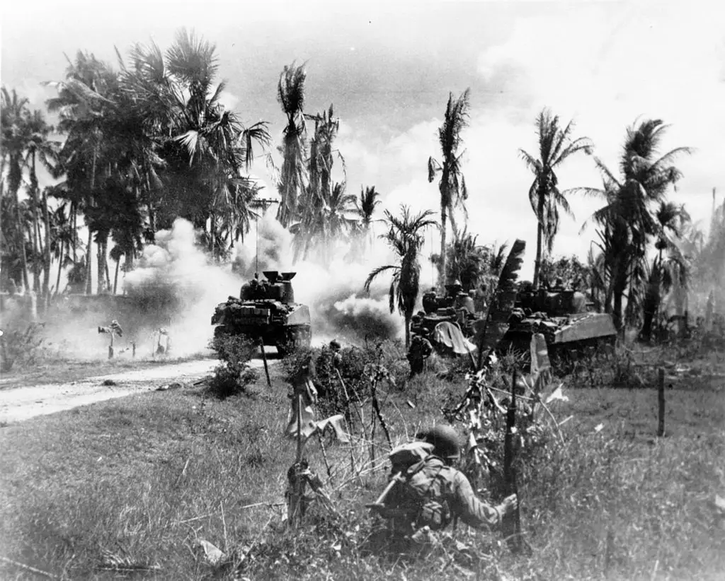 القوات الأمريكية من الفرقة رقم 185، تتحصن خلف الدبابات المتقدمة ضمن المواقع اليابانية في جزيرة باناي) في 18 مارس 1945 