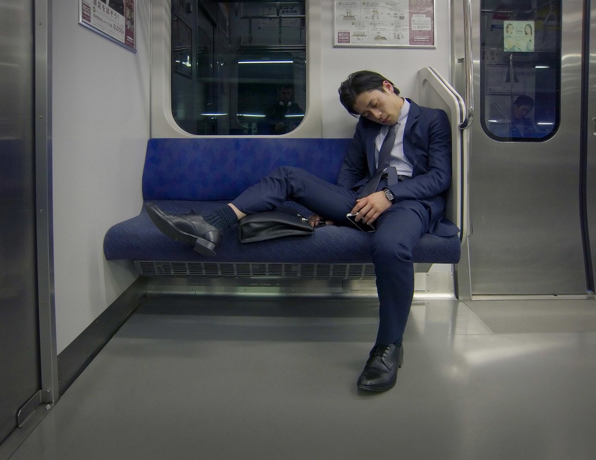 رجل مرهق نائم في قطار في طوكيو