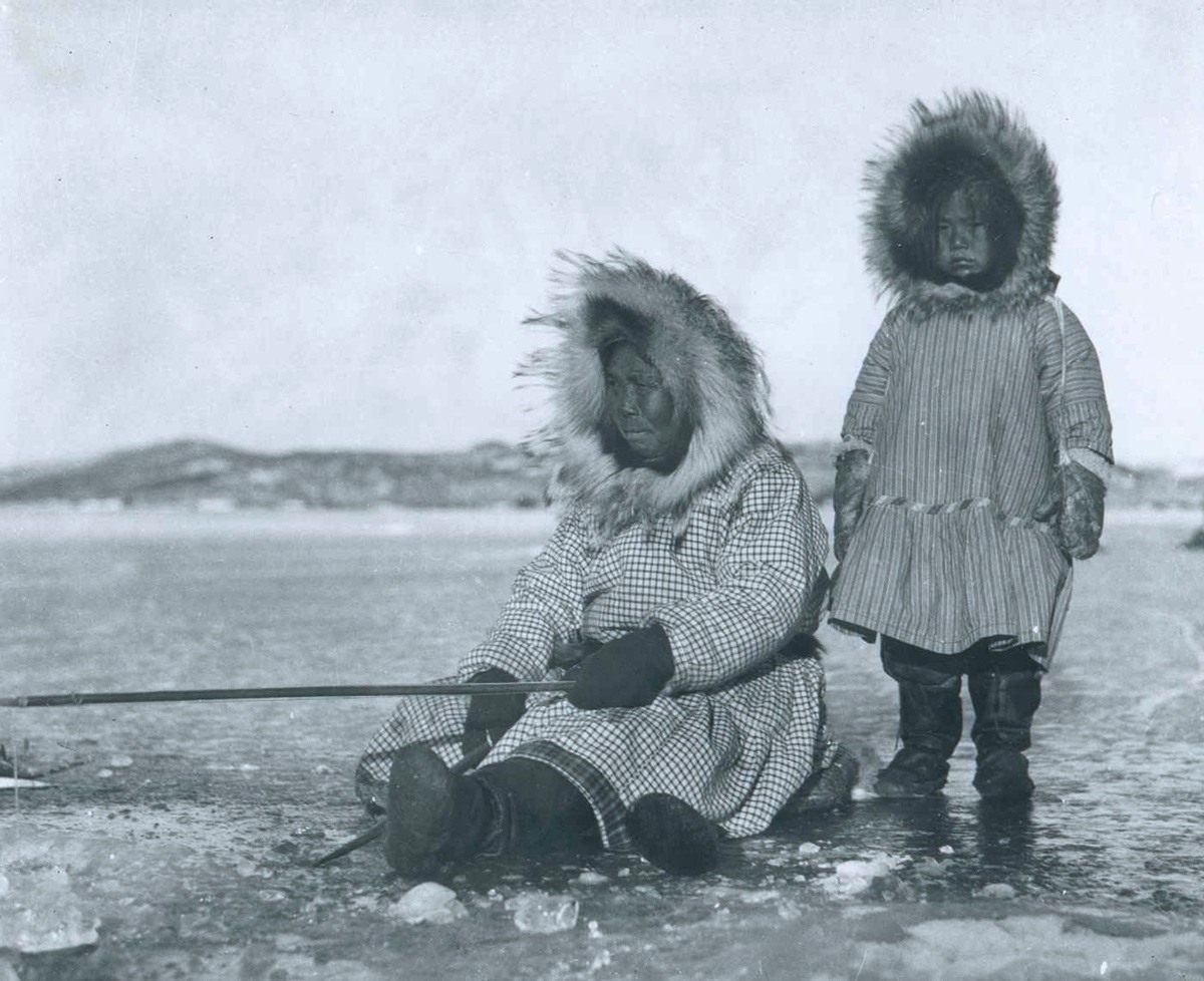 طفلة من الأسكيمو تقف مع والدتها على الجليد