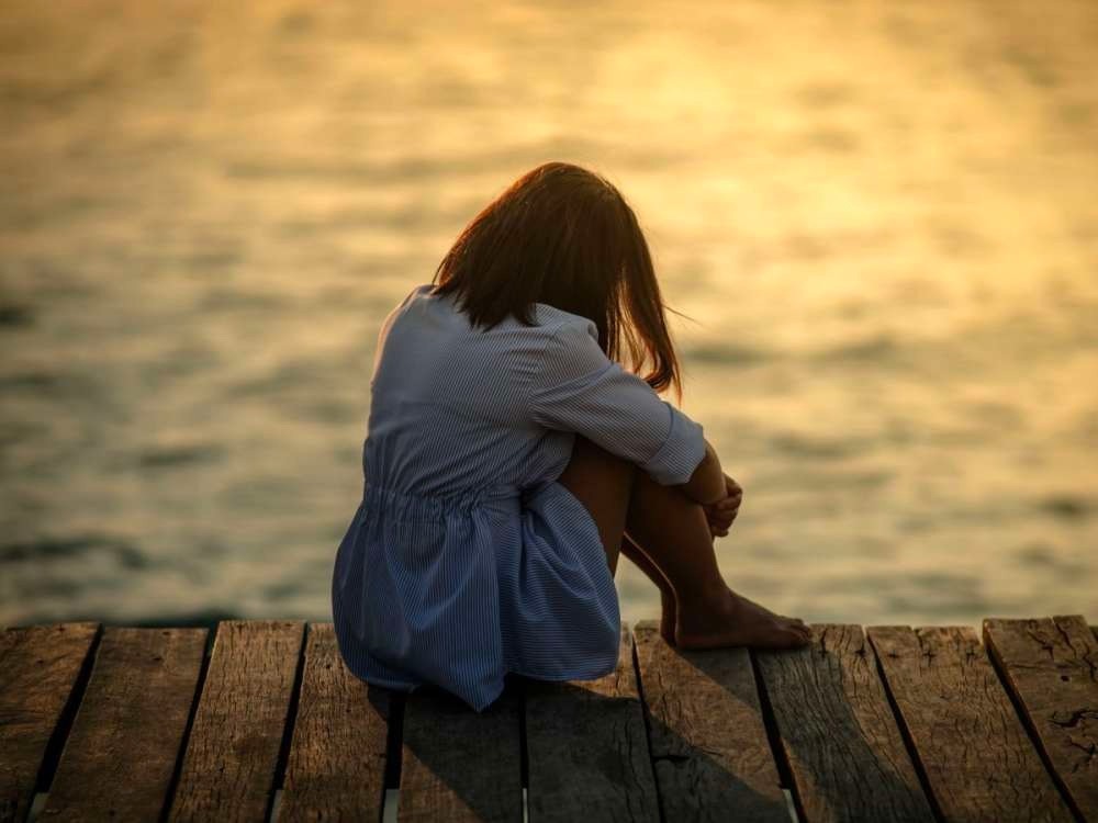 فتاة جالسة وحيدة أمام البحر