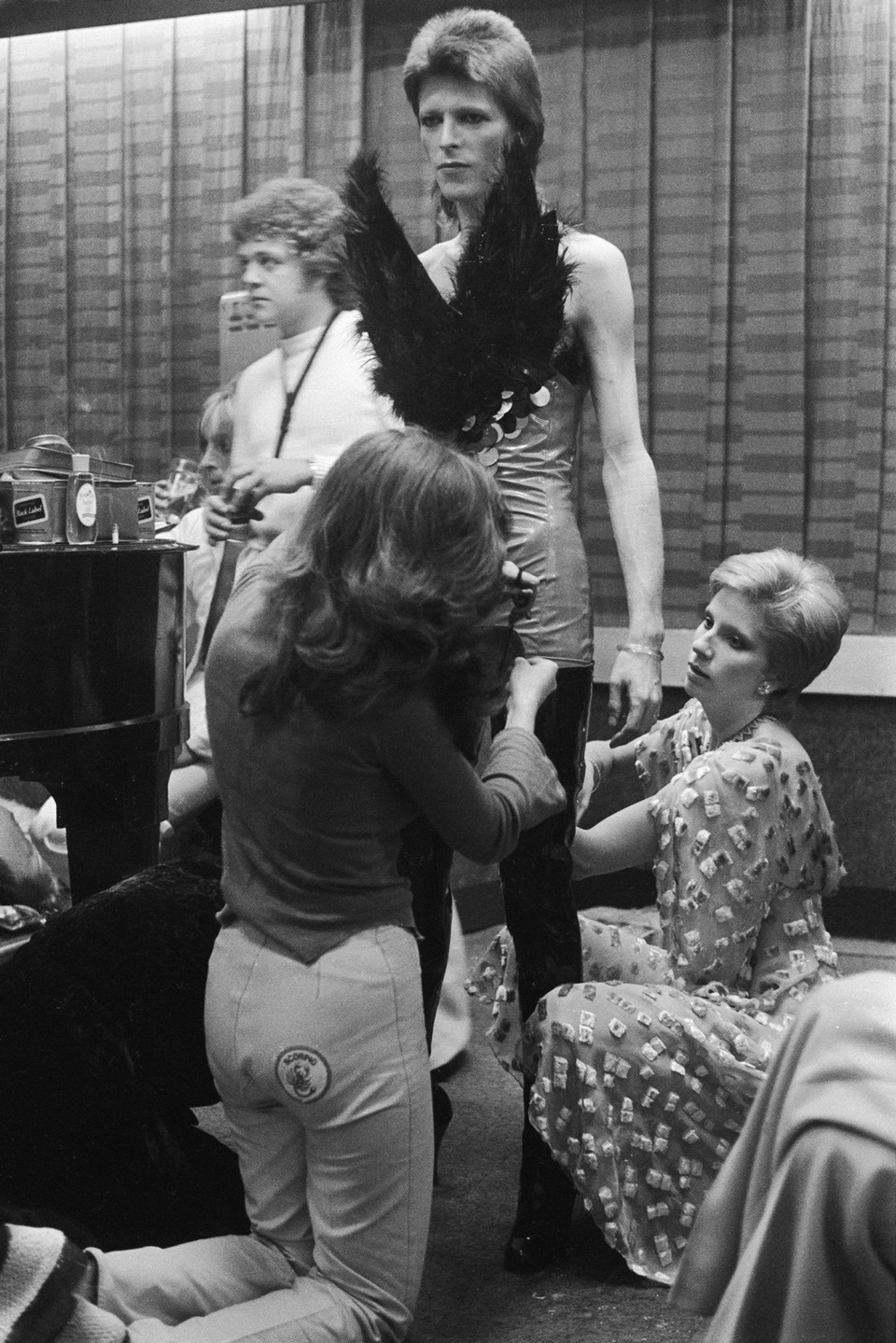 (دايفيد بوي) سنة 1973 وهو يرتدي أحد الأزياء الفريدة من إعداد زوجته (آنجي بوي) على يمين الصورة ومساعدتها.