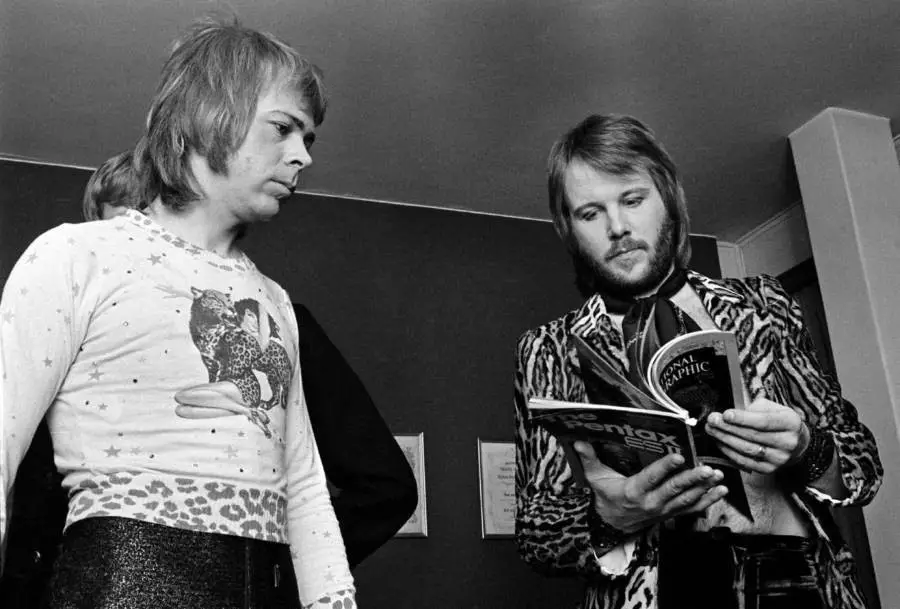 (بيني أندرسون) و(بيورن أولفايوس) من فرقة (آبا) يطالعان نسخة من مجلة (ناشيونال جيوغرافيك) خلف الكواليس في (كوبنهاغن) بالدنمارك سنة 1975.