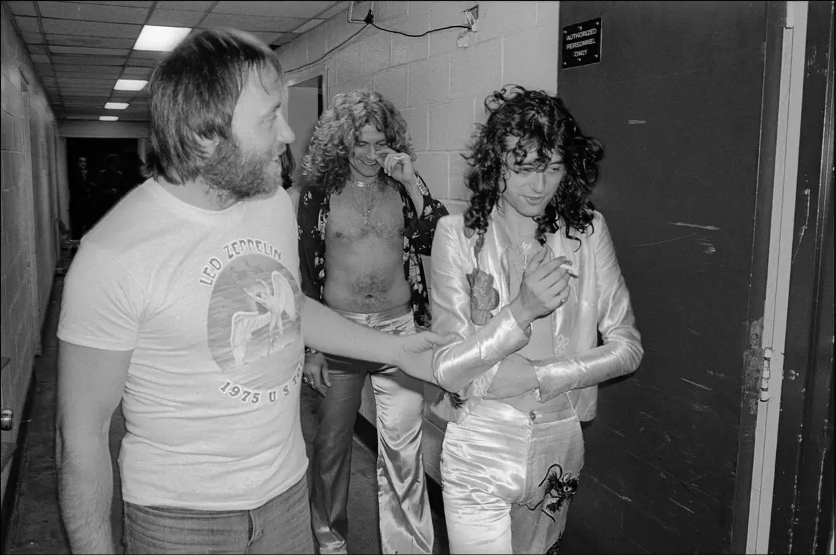 (جيمي بايج) عازف الغيتار في فرقة (ليد زيبلين) [في اليمين إلى الأمام] والمغني (روبرت بلانت) [في مركز الصورة إلى الخلف] خلف الكواليس في قاعة (ماديسون سكوار) في نيويورك في سنة 1977.