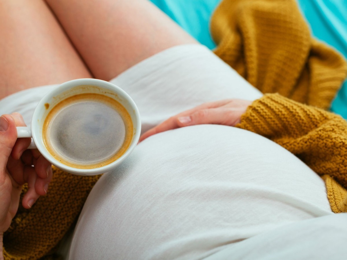 امرأة حامل تحمل كوب قهوة