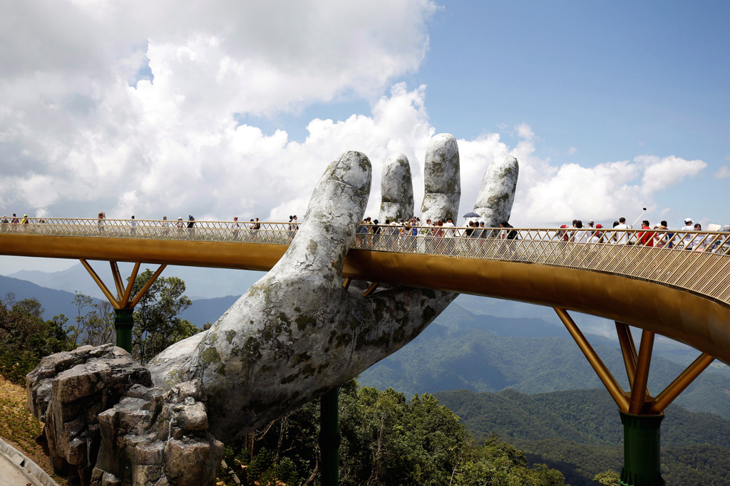 سياح يتمشون عبر مجسم ضخم لليد البشرية على الجسر الذهبي في منتجع (بانا هيلز) Ba Na Hills في فيتنام