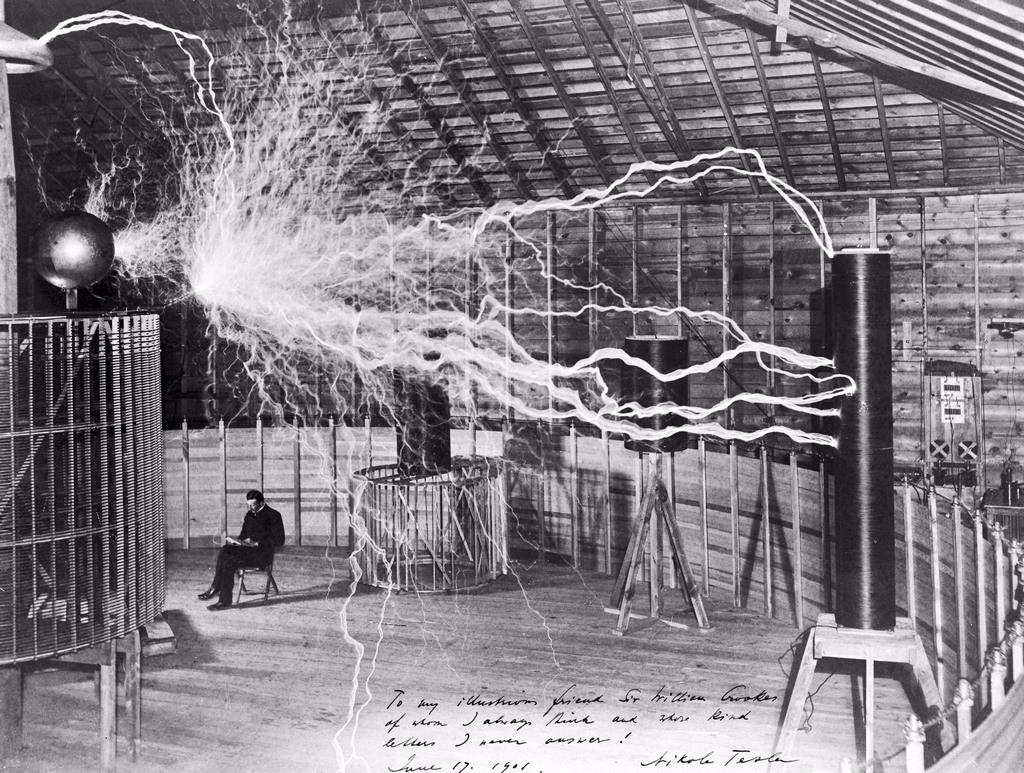 المخترع الأمريكي-الصربي (نيكولا تيسلا) في مختبره في (كولورادو) حوالي سنة 1899، هنا يظهر جالساً بصدد قراءة كتاب بجانب مولد التيار القوي وجهاز الإرسال الممغنط الضخم خاصته بينما تنتج هذه الآلة شرارات هائلة من التيار الكهربائي.