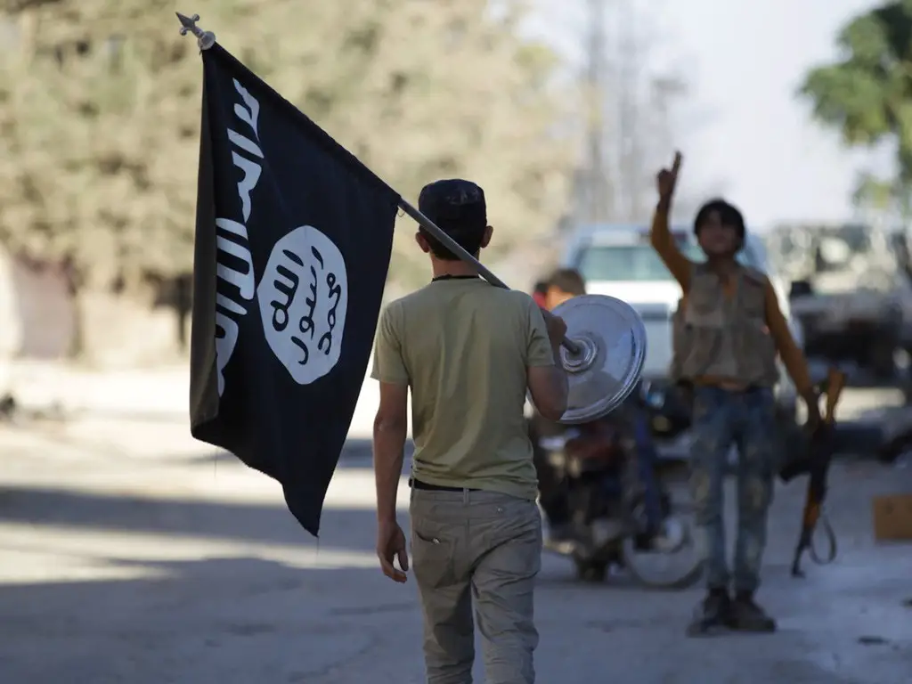 مقاتل ثائر في سوريا ينزع علم تنظيم الدولة في العراق والشام.