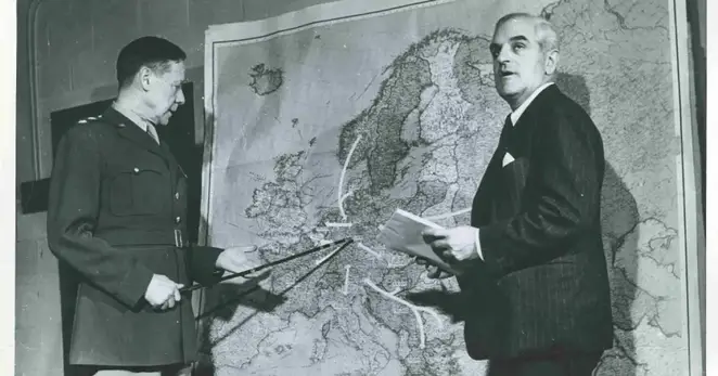 يقف الجنرال الأمريكي (ألين غولين) و(فريد كيه هوهلر) مدير شعبة النازحين في الأمم المتحدة، أمام خريطة للتنبؤ بحركة اللاجئين الأوروبيين في الحرب العالمية الثانية.