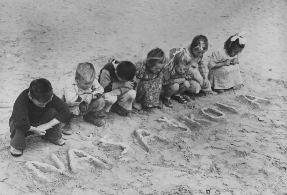 صورة تبرز أطفالا كرواتيين يخطّون على الرمل كلمة ”مدرستنا“ بلغتهم الأم في مخيم الطلمبات في مصر، سنة 1945. صورة: United Nations Archives