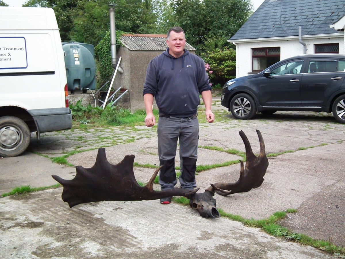 (ريموند مكيلروي) يقف أمام جمجمة وقرون أيل أيرلندي التقطتها شبكته أثناء صيده للأسماك في بحيرة (لاف نايج) في إيرلندا الشمالية.