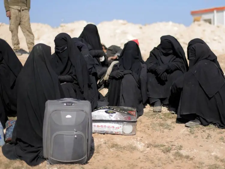 نساء يجلسن بقرب أغراضهن بالقرب من باغوز في سوريا في 12 فبراير 2019.