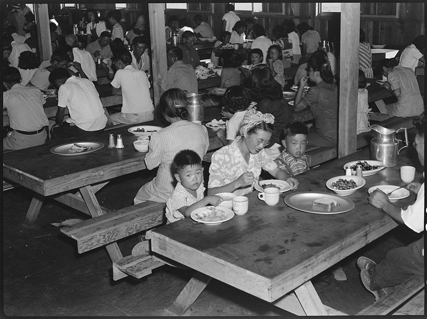 ورد في التعليق الكامل على هذه الصورة: «مركز مانزانار للترحيل»، في (مانزانار) بكاليفورنيا. وقت تناول الطعام في قاعة لتقديم الطعام في هذا المركز الخاص بالمواطنين الأمريكيين من أصول يابانية.